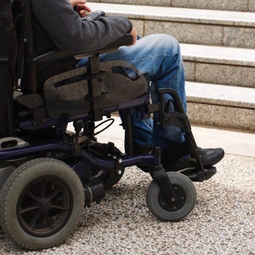 Wheelchair user in front of staircase barrier